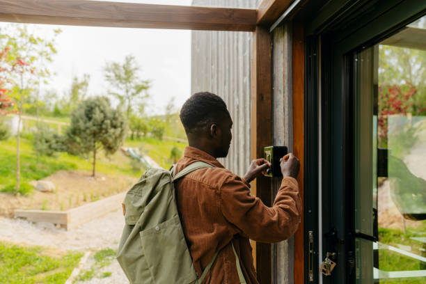 Arrival into my weekend getaway log cabin Photo of a young African American man, who has jus arrived into his rental home for the weekend - a cabin on the riverbank in the woods - using a lock box to take the keys key package stock pictures, royalty-free photos & images