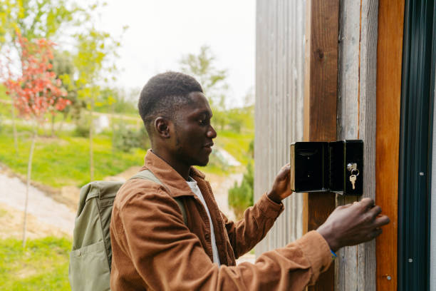 Arrival into my weekend getaway log cabin Photo of a young African American man, who has jus arrived into his rental home for the weekend - a cabin on the riverbank in the woods - using a lock box to take the keys key package stock pictures, royalty-free photos & images