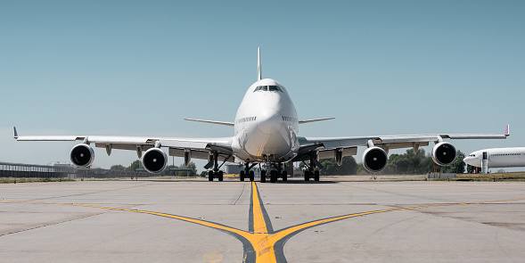 hot exhaust coming out of the engine and distorts the visibility. Frontal symmetric view of two-storey jumbo jet on a ground.