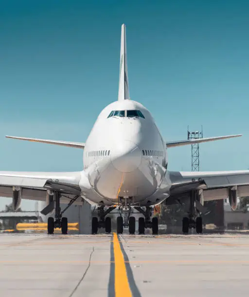 Frontal close-up view of two-storey jumbo jet on a ground on a sunny day.