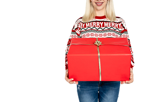 Unrecognizable woman holding Christmas present. Unrecognizable woman promoting sales with a gift dressed in a Christmas sweater and wearing a Santa Claus hat. Studio background white