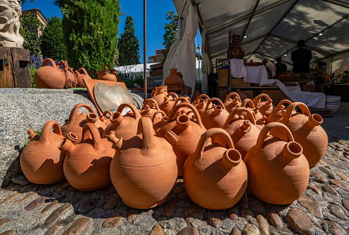 Set of handmade clay and ceramic jugs displayed on the floor of a traditional crafts market in Salamanca. Earthenware drinking jug.