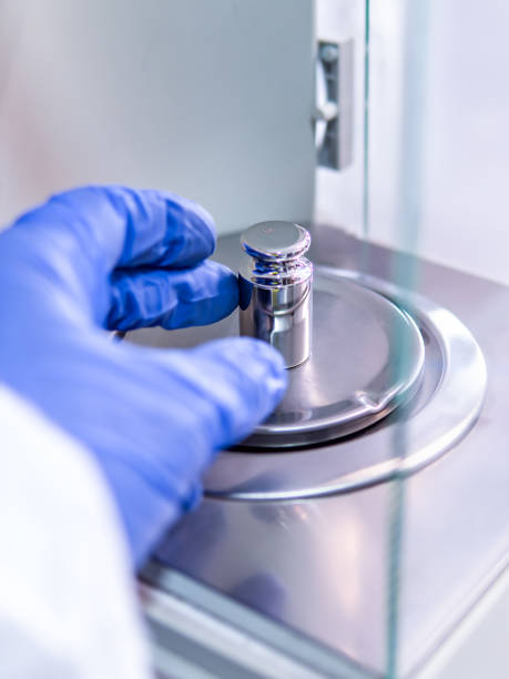 istock A operator's hand is holding steel calibration weight to place on the analytical balance. Concept of quality control in a laboratory. 1694990607