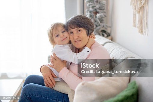 Grandmother and child, sitting at home on the sofa, hugging, pure love between generations