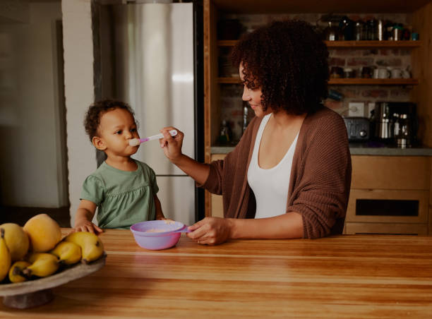 istock Biracial mother feeding daughter in kitchen at home 1695022817