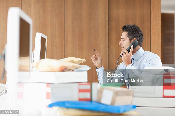 Biznesmen Rozmawia Przez Telefon Za Paczki - zdjęcia stockowe i więcej obrazów 30-34 lata - 30-34 lata, 30-39 lat, Biurko