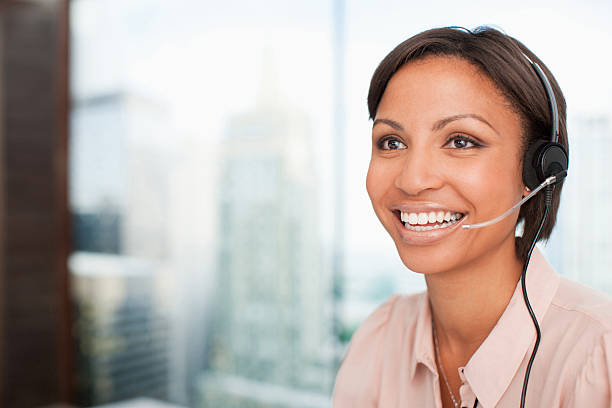 mulher de negócios sorridente com fone de ouvido - female customer service representative looking at camera technology - fotografias e filmes do acervo