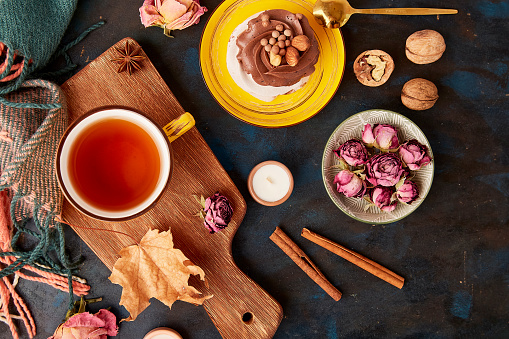 Aesthetic Pavlova cake, Tea Cup. Autumn aesthetics tea time vibes flat lay among dry roses, leaves, blueberry, walnuts.