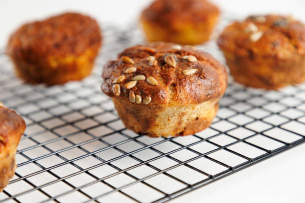 Close-up on yellowish brown baked crusty corn muffins with sesame seed on top, served on grid