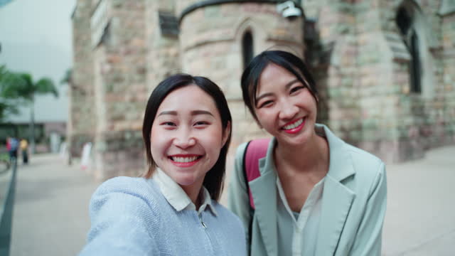 Young couple Asian woman as solo travel using mobile phone taking a selfie talking like influencer during vacation at Brisbane city