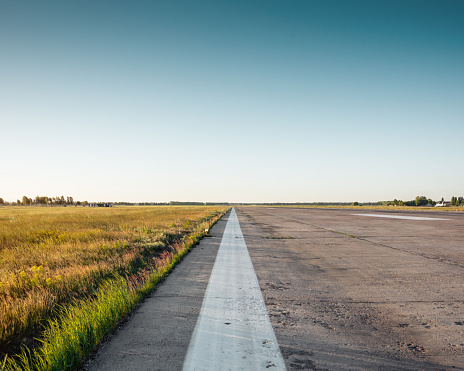 Minimalistic wide angle shot of empty airport runway at sunset - edge of runway and field surrounding it.