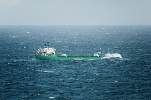 A general cargo ship in the sea with rough sea hitting its bow