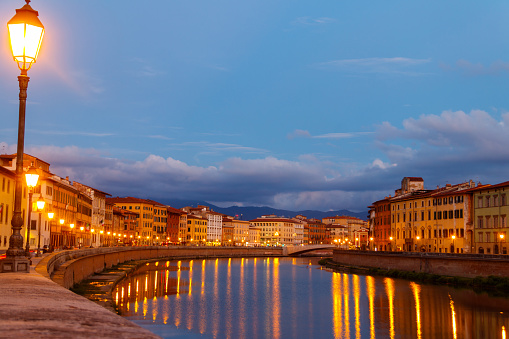 Panoramic view of the old town of Pisa and the Arno river at twilight, Italy. Night cityscape