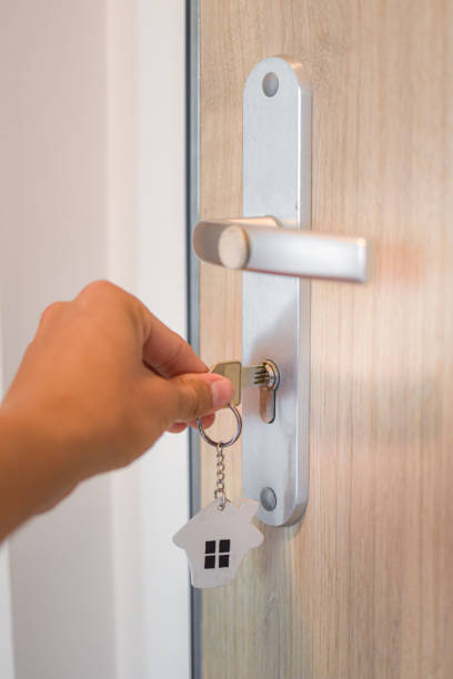 istock Hand unlocking door with key with house pendant. 1695151407
