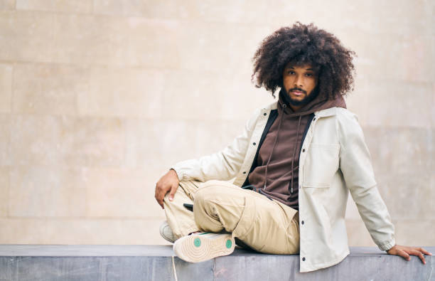 istock young afro man sitting on a step of a square looking at the camera 1695152098