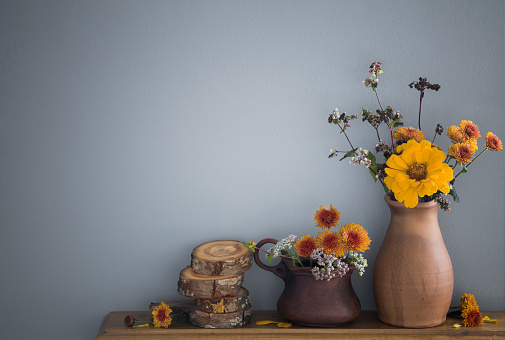 autumn flowers in rustic ceramic vase on background gray wall