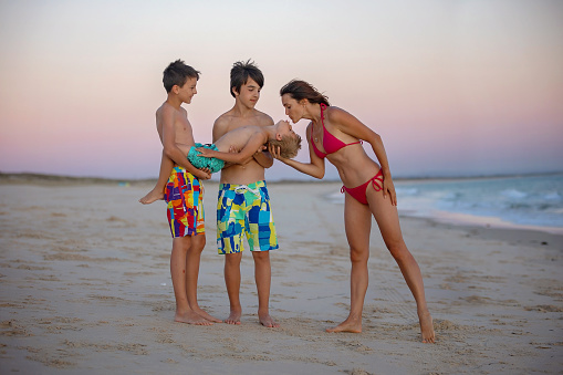 Happy children, boys, playing on the beach on sunset, kid cover in sand, smiling, laughing, enjoying some fun