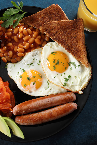 Traditional American breakfast with fried egg,toast,bacon and sausage on wooden table