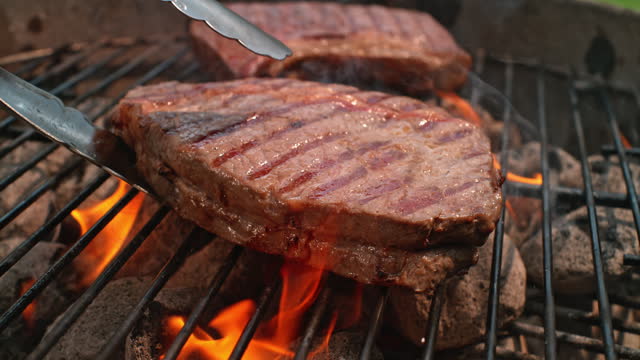 SLO MO Big steak being turned on the charcoal grill