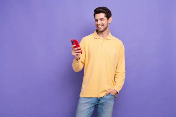 Photo of confident handsome man dressed yellow shirt typing apple samsung iphone modern device isolated purple color background.