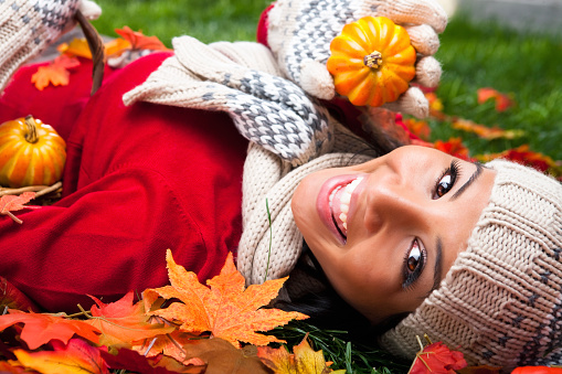 Happy Filipino female laying on fall grass with warm clothing