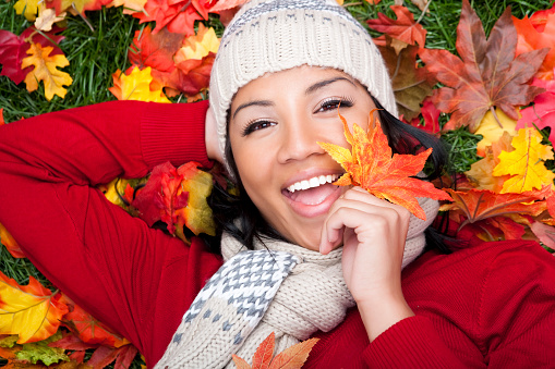 Happy Filipino female laying on fall grass with warm clothing