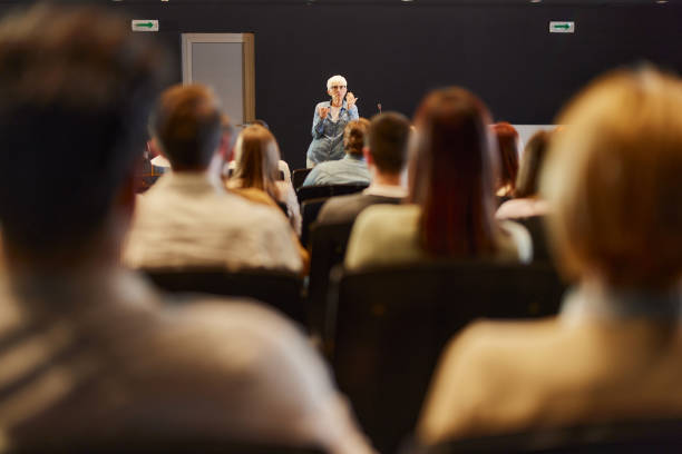 istock Senior public speaker talking on a conference at convention center. 1695209191