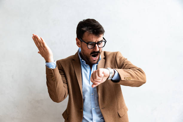 istock Close up Smiling Young Businessman making faces Wearing Eyeglasses, Looking at the Camera Against Gray Wall Background with Copy Space. Successful Business Person in Formal Wear Portrait 1695213636