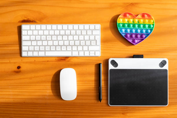 On a desk without people several digital tools for digital drawing and illustration. A rubber heart with the colors of the rainbow for LGTBI collective drawing.