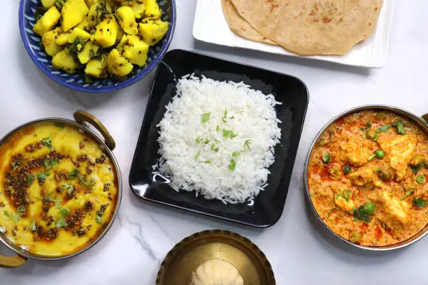 Indian vegetarian Thali or platter includes Aloo ki sabji, dal rice, Roti bhaji, Matar Paneer, Sheera or suji ka halwa, chapati. Indian food is served in a Silverplate or thali. Copy Space. Veg Thali