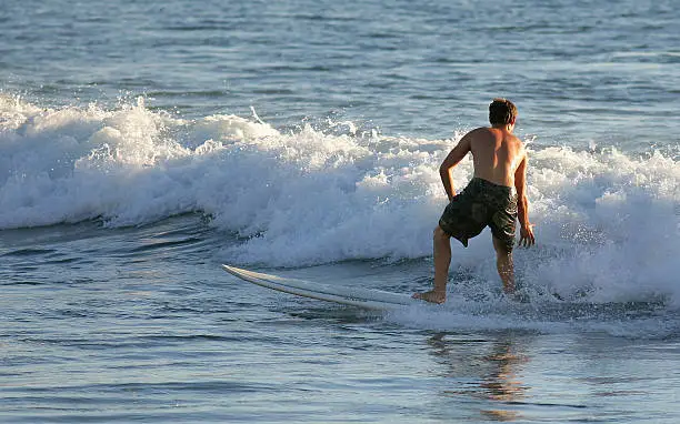 A surfer standing on his surfboard in the Sea
