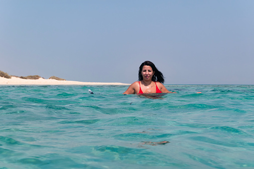 Lady in bikini in the water of a deserted island offshore, middle east