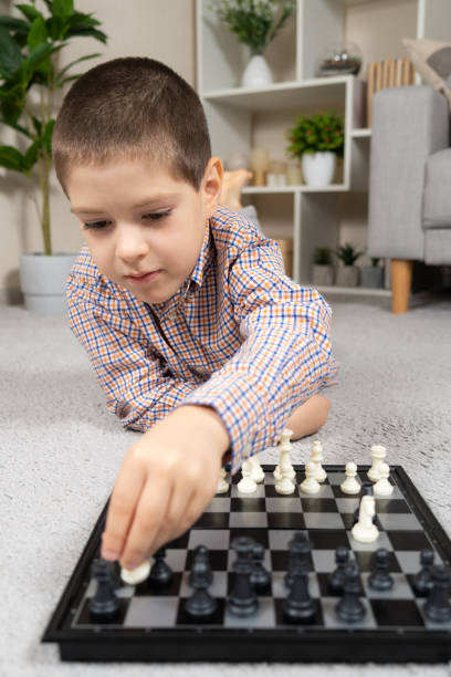 petit garçon jouant aux échecs. jeux de société pour enfants - chess skill concentration intelligence photos et images de collection