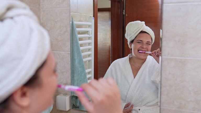 Young Woman Brushing Her Teeth In The Bathroom