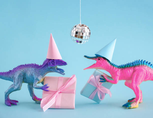 istock Two funky dinosaurs with gift boxes and disco ball on pink background. Happy birthday card idea. 1695262475