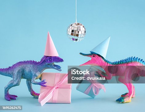 Two funky dinosaurs with gift boxes and disco ball on pink background. Happy birthday card idea.