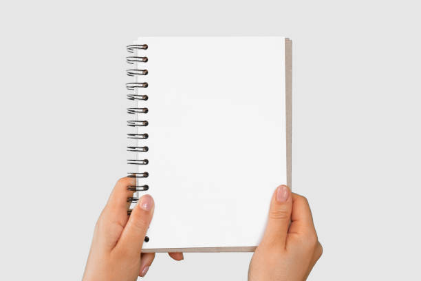 istock Female Hand Holding Notepad with blank Page Isolated On Green Background. Close Up. Chroma Key Screen. Woman's Hand with Empty Card Paper MockUp. Advertisement gesture. Notebook Mock Up. Greenscreen 1695263378