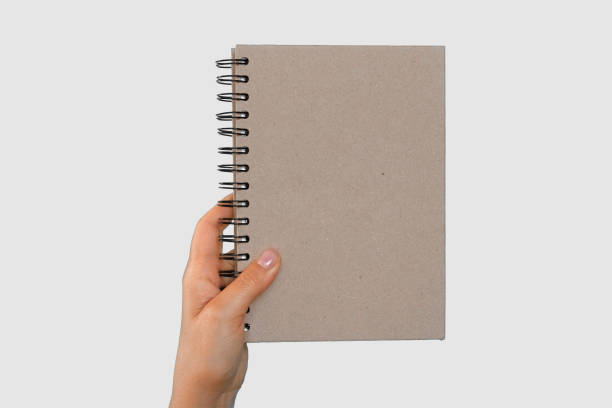 istock Female Hand Holding Notepad with blank Page Isolated On Green Background. Close Up. Chroma Key Screen. Woman's Hand with Empty Card Paper MockUp. Advertisement gesture. Notebook Mock Up. Greenscreen 1695263380