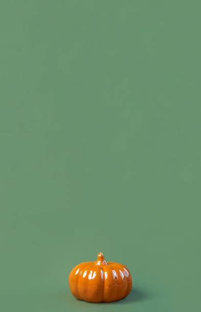 istock Halloween vertical background with orange pumpkin. Modern Holiday design. Fall party border on olive green natural color backdrop. Flat lay, top view, copy space. Thanksgiving trendy fall decoration 1695271652