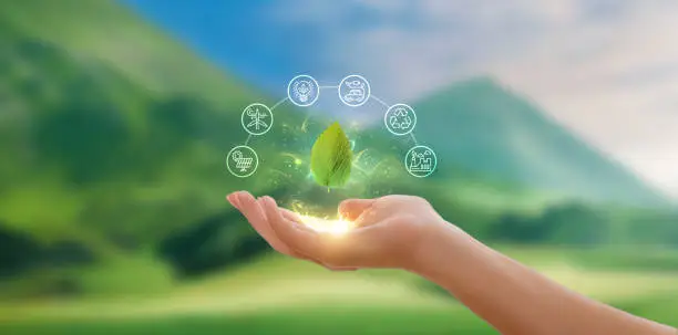 Hand holding a green leaf with icons representing renewable and sustainable energy sources