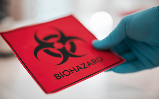 Hand, science and a sign for biohazard in a laboratory to label a chemical for safety warning or danger. Healthcare, medical and biology with a scientist closeup in a lab for research or innovation