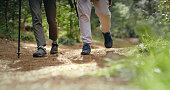 Walking, feet and people hiking in forest, nature or shoes on the ground with green, trees and plants in soil or environment. Legs, closeup and trekking journey in countryside, woods and dirt path