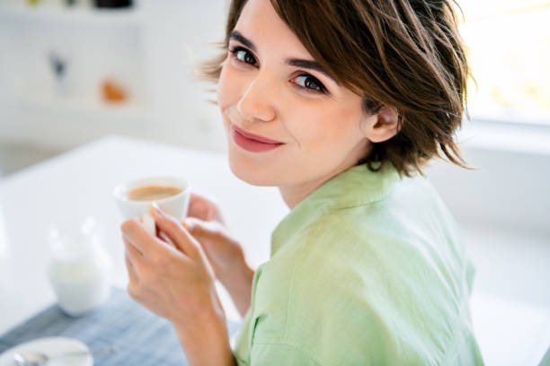 朝のアメリカーノコーヒーを屋内で飲む愛らしいかわいい女性の写真 家の台所 - stereotypical housewife women domestic kitchen brown hair ストックフォトと画像