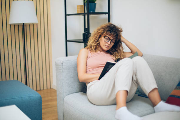 istock Young beautiful woman reading a book on a sofa 1695351174