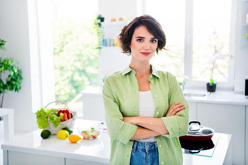 Photo of cool confident lady dressed green shirt arms crossed preparing meals indoors house kitchen.