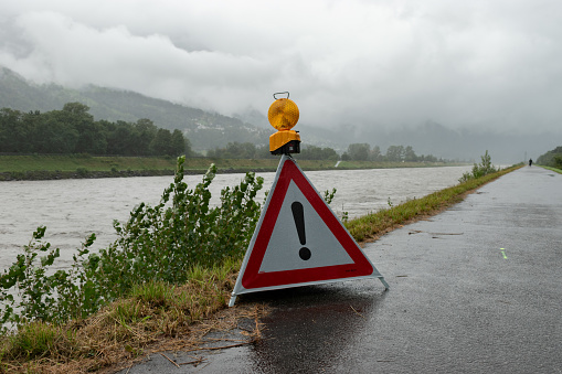 Sevelen/Vaduz, Switzerlan/Liechtenstein, August 28, 2023 Caution sign at the dam of the rhine river during a heavy flood and a severe rain shower