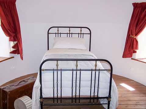 Old fashioned Victorian single bed, made from wrought iron, in a round bedroom