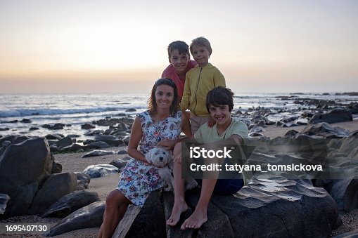 Happy children, enjoying sunset over the ocean with their family, rocky beach