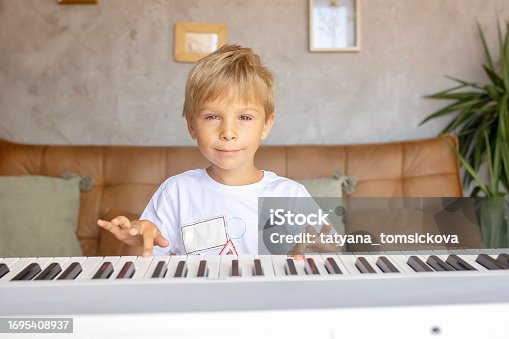 Child, blond boy, playing piano at home