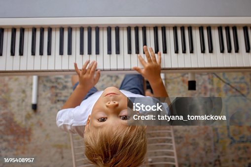 Child, blond boy, playing piano at home